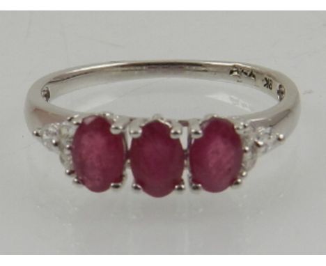 A 9 carat white gold, ruby, and white stone ring, set three oval cut rubies. 