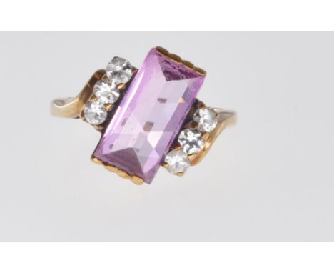 A 10k gold fancy cut synthetic sapphire and white stone ring having a rectangular cut pick sapphire flanked by six round cut 