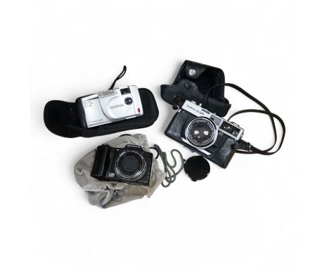 A cased Olympus 35SP camera, together with two more recent digital cameras