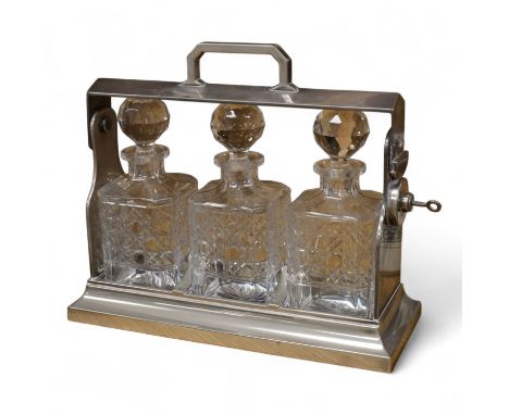 A silver plated three bottle tantalus, 34cm wide.