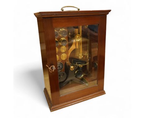 A Victorian binocular brass microscope, unsigned, in a fitted, glass fronted case with a good selection of alternative lenses