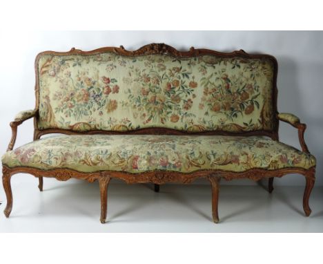 A large 19th Century carved and painted French Settee, the shaped back over outsplayed arms, and a carved serpentine frieze w