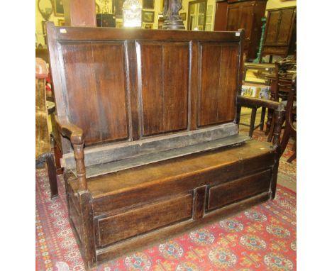 A late 18th Century oak Hall Settle Bench, the three panel back over a lift up seat with decorated iron hinges, and a two pan