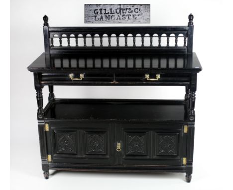 An ebonised carved oak Hall Buffet, with rail back over two frieze drawers, an under shelf and two press doors each with bras