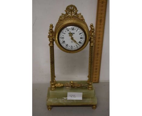 A 20th Century mantel clock by Martim with decorative brass column body and a polished onyx base
