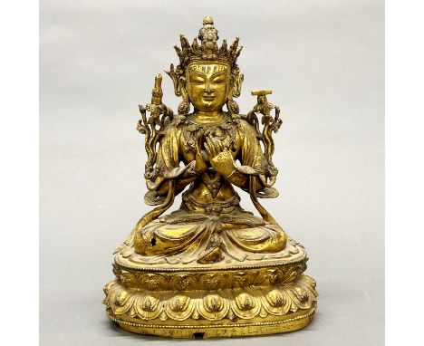 A Tibetan gilt bronze figure of a seated Buddha embellished with sacred symbols, H. 25cm. Slight age damage to metal.