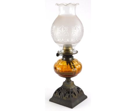 A late Victorian cast iron oil lamp, with brass fitting, amber tinted reservoir and parcel gilt base, later shade, the base 3
