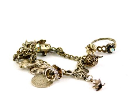 A silver charm bracelet and dress ring, the charm bracelet with various charms including three leaf clover, fish, penguin, co