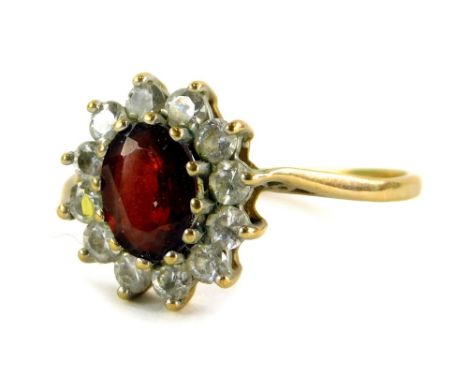 A 9ct gold floral cluster ring, the central garnet surrounded by various CZ stones, in a claw setting, on pierced design shou