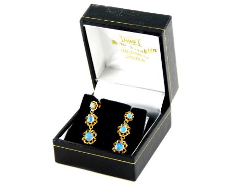 A pair of opal drop earrings, each of three tier drop, central opal in a pierced floral design border, yellow metal stamped 1