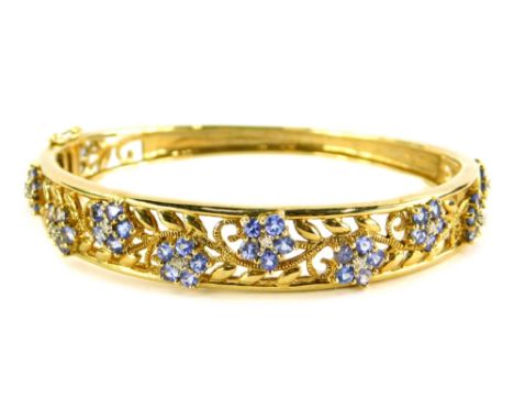 A hinged bangle, the top floral engraved design set with purple coloured stones and central CZ stones, on a clip clasp with t