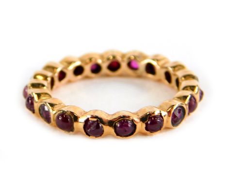 A garnet eternity ring, set with various cabochon cut stones, in a rose gold coloured setting, unmarked, ring size K½, 2.9g a