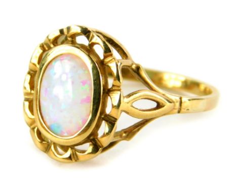 A 9ct gold opal dress ring, the oval opal in a rub over setting, with pierced design, gold metal flower type border, on splay