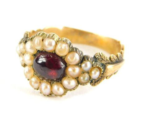 A Victorian memorial ring, set with cabochon garnet stone, surrounded by seed pearls, with scroll and acanthus leaf shoulders