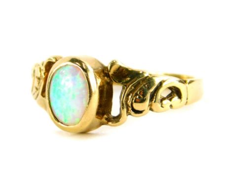 A 9ct gold opal dress ring, with central oval cut opal, in a rub over setting, with rococo style shoulders, ring size K½, 1.9