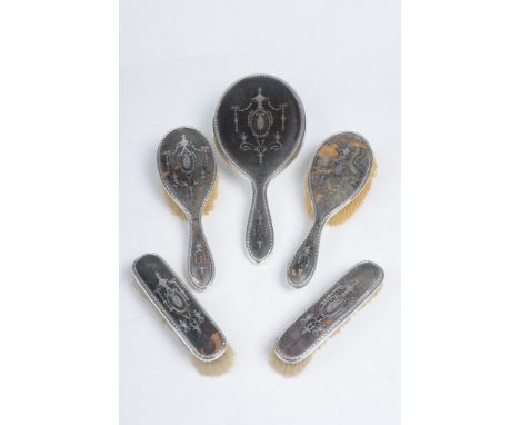 A George V five piece silver and faux tortoiseshell brush dressing table set
Comprising hand mirror, two clothes brushes and 