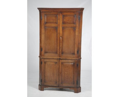 A George III oak panelled freestanding corner wall cupboard
With a cavetto cornice above a pair of cupboard doors, each with 