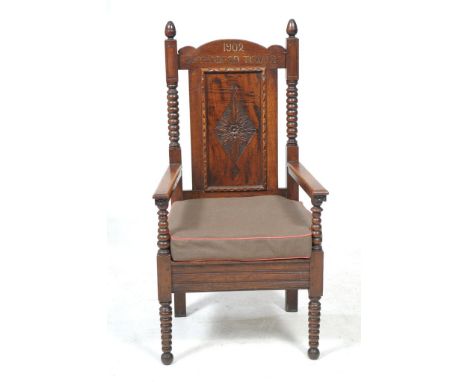 An early 20th Century oak Eisteddfod armchair, Towyn 1902
With an arched cresting rail inscribed and dated 1902 above a panel