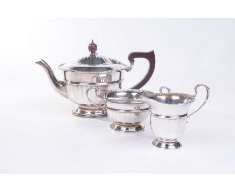 A George V silver three-piece tea service
The teapot of rounded pedestal form with fluted sides and reeded borders, flanked b