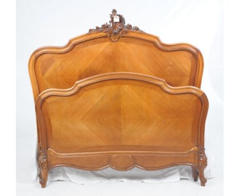 A French Louis XV style walnut bed
With a waisted panel back with a shell leaf and flower pediment, quarter veneered back rai