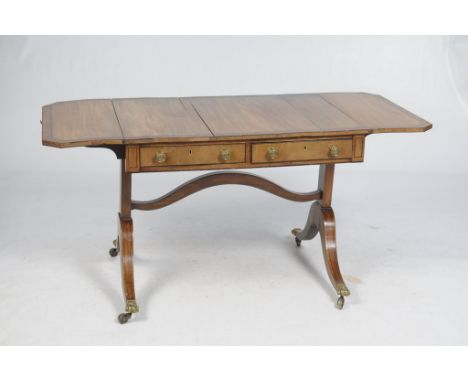 An early 19th Century inlaid mahogany and crossbanded sofa table
The rectangular top with two hinged canted leaves, with a br