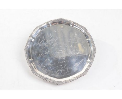 A George V silver card tray
Of scalloped rosette form, raised on three scroll supports,s the rope work border encircling comp