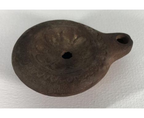 A terracotta oil lamp, probably Roman, of typical form and decorated with geometric designs, 8cm long 