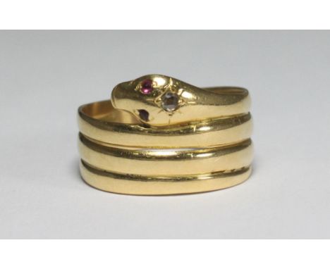 An 18ct gold ring modelled as a stylised serpent, the head set with a diamond and two small coloured stones for eyes, gross w