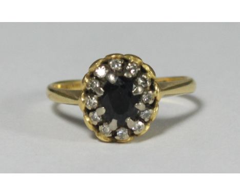 An 18ct gold ring, the top centrally claw set with a faceted sapphire coloured stone, surrounded by 12 small diamonds, gross 