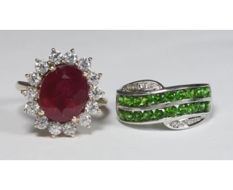 A 9ct gold dress ring set with a large oval faceted glass or paste ruby coloured stone, surrounded by 14x white stones, 5.7g,