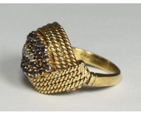 An indistinctly marked yellow metal (tests as 18ct gold) ring, the top set with 26 small sapphire coloured stones and three s