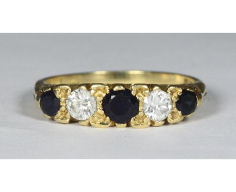 An 18ct gold bridge ring with carved mount, set with three round sapphires and two round brilliant-cut diamonds, diamonds wei