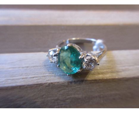 18ct White gold ring set oval emerald flanked by two brilliant cut diamonds 