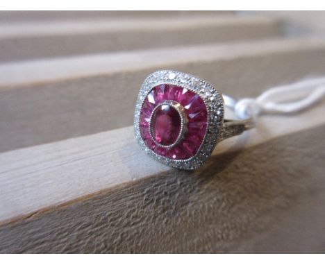 Platinum ring set central ruby bordered by a halo of calibre cut rubies and diamonds 