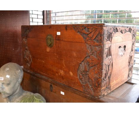Oriental carved camphor wood trunk decorated in deep relief with stylised flowers, the hinged lid above a brass hasp and stap