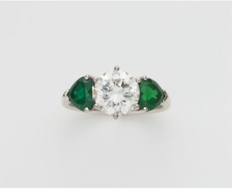 Dreisteine-Ring mit Diamantsolitär18 kt Gelbgold, rhodiniert. Kantige Schiene gefasst mit zwei Smaragden in Herzform (jeweils