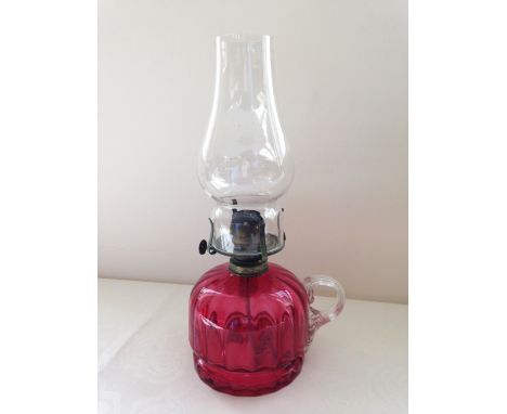 An antique cranberry glass hand held oil lamp.