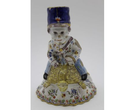 A French faience hand bell, modelled in the form of a postman riding a tortoise, polychrome hand painted in the Quimper style