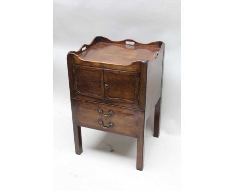 A Georgian mahogany bedside commode unit of square form, with pierced handle uprights two panelled cupboard doors over slide 