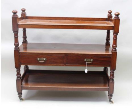 An Edwardian mahogany three tier dumb waiter, the middle tier fitted two brass handled drawers, raised on ceramic castors, 11