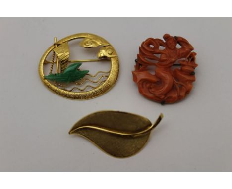 A 14k gold brooch, pierced & chased, with a jade mounted junk at sea, together with a leaf form brooch stamped .750, and a ca