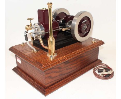 A very well engineered model of a 4 Stroke Single Cylinder Petrol Engine, finished in maroon and raised on wooden plinth and 