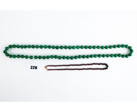 A STRING OF GREEN JADE BEADS, 34 ins long and graduated garnet polished BEAD NECKLACE, 16 ins long.  (2)   