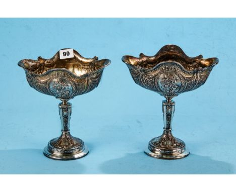 A PAIR OF EDWARDIAN FRENCH STYLE SILVER PLATED ON COPPER COMPORTS embossed with panels of cherubs, raised on pedestal bases w