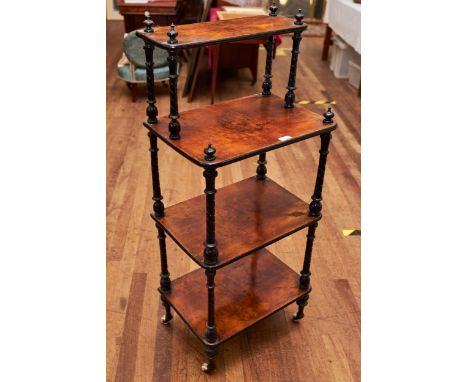 A VICTORIAN WALNUT AND EBONISED FOUR TIER WHATNOT raised on turned legs with brass and ceramic castors, 20 ins wide.    