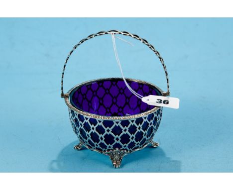 A GEORGE V CIRCULAR PIERCED SILVER SWING HANDLE SUGAR BASIN, blue glass liner, raised on scroll feet, maker: WM Hutton &amp; 
