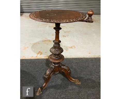 A Victorian walnut sewing table of circular form, with a foliate carved outer border and rotating swing bracket, raised upon 