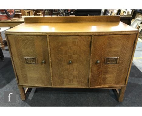 A 1930s light oak sideboard, the ledge back over an angled front and central three drawers enclosed by a parquetry inlaid doo