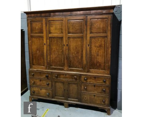 A George III oak house keeper's cupboard, the shelf interior enclosed by four crossbanded and floral and shell paterae doors 