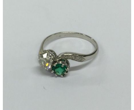 An emerald and diamond two stone crossover ring in platinum setting. Approx. 4 grams. Est. £800 - £1200.